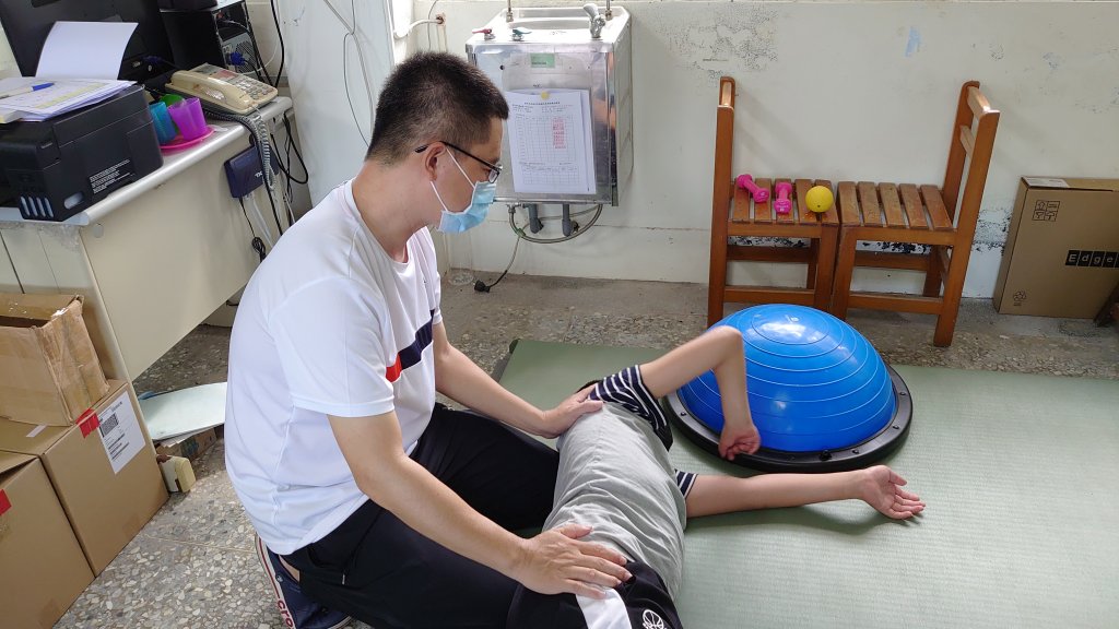 榮鑫老師(左)透過肢動課程,陪伴小豪進行復健。/臺東縣政府教育處提供。